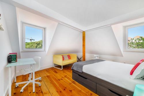 a bedroom with a bed and a desk and two windows at WHome | Premium River View Apartment in Lisbon