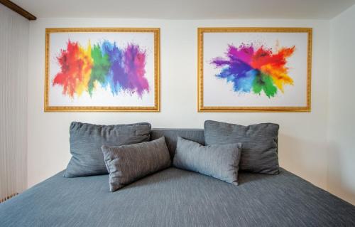 a bed with three pillows and two paintings on the wall at MoselUnion - "schlafen & genießen" in Cochem