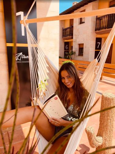 a woman sitting in a hammock reading a book at Las Casitas de Santillana in Santillana del Mar