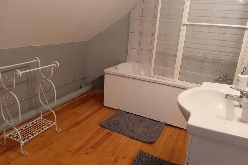 a bathroom with a white tub and a sink and a bath tub at la maison de maxime in Courcelles-lès-Gisors