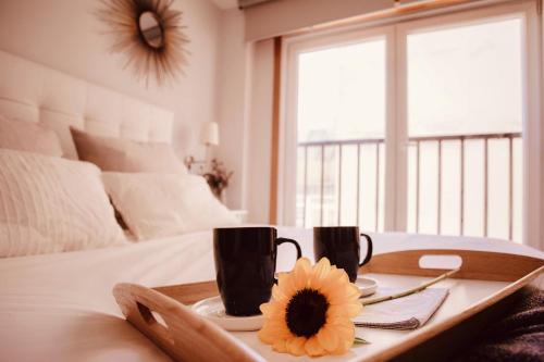 een dienblad met twee koffiekopjes en een bloem op een bed bij San Amaro Beach Apartment in A Coruña
