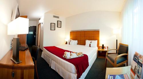 a hotel room with a bed and a desk at Holiday Inn Bordeaux Sud - Pessac by IHG in Pessac