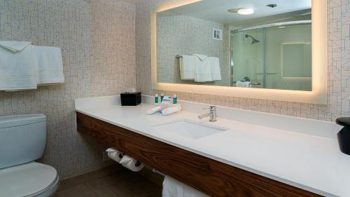 a bathroom with a sink and a toilet and a mirror at Holiday Inn Express Fullerton-Anaheim by IHG in Fullerton