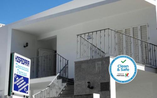 a sign in front of a white building with stairs at Hospedaria Descansa Pernas in Monchique