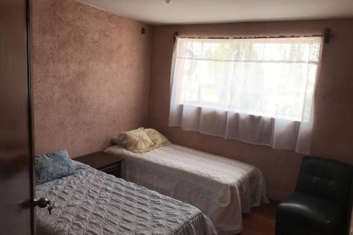 a small bedroom with two beds and a window at Casa Matlaltlkali - Zonas Arqueologicas y Parques Temáticos in Mexico City