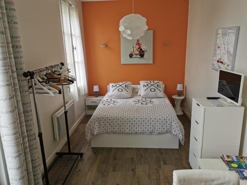 - une chambre avec un lit et un mur orange dans l'établissement Studio des Stuarts, à Dol-de-Bretagne