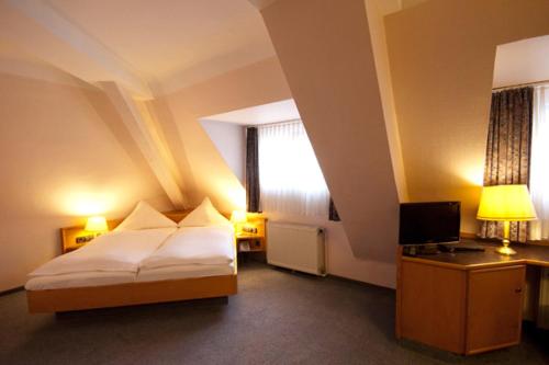 ラントシュトゥールにあるホテル ゴールディンガーのベッドとテレビが備わるホテルルームです。