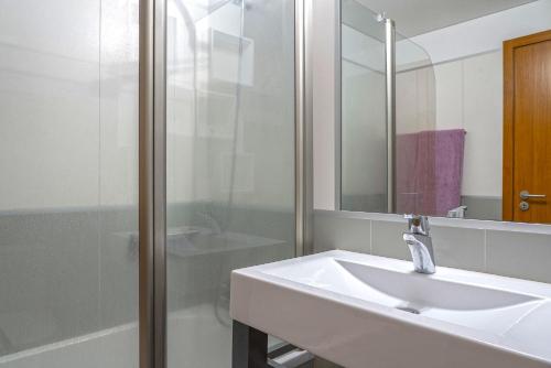 La salle de bains blanche est pourvue d'un lavabo et d'un miroir. dans l'établissement Sunset Apartment by HR Madeira, à Funchal