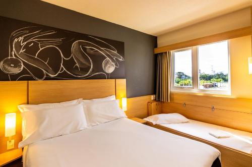 a hotel room with two beds and a window at Ibis Porto Alegre Assis Brasil in Porto Alegre