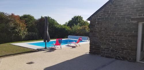 two chairs and an umbrella next to a swimming pool at Chambre d'hôtes Morbihan Gwenva in Sainte-Brigitte