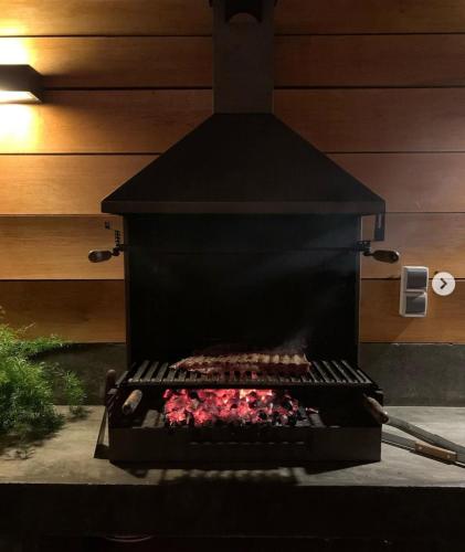 a black barbecue grill with red meat in it at Las Casitas de Santillana in Santillana del Mar
