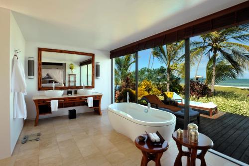 a bathroom with a tub and a sink and a desk at The Residence Zanzibar in Kizimkazi