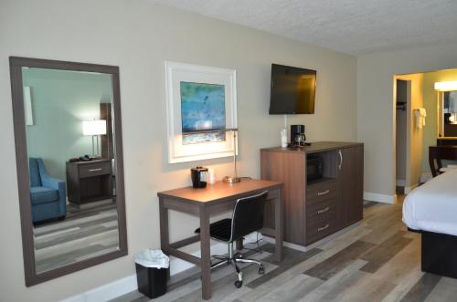 a hotel room with a desk and a bed and a mirror at Opal Hotel & Suites in Orlando