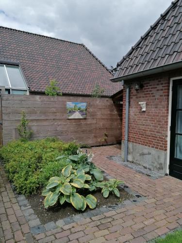 a house with a brick wall and some plants at B&B d'n Uilenhof Haren in Haren