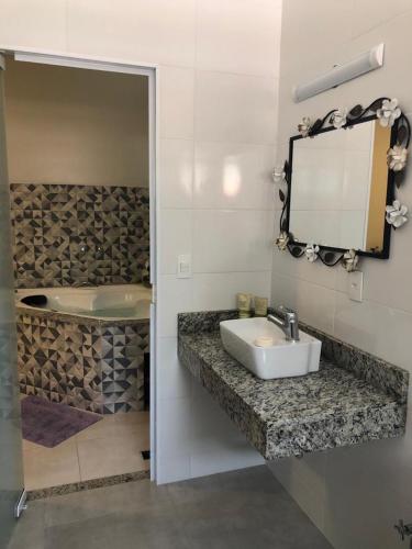 a bathroom with a sink and a mirror and a tub at Hotel Pousada Riacho da Areia in Águas de Lindóia