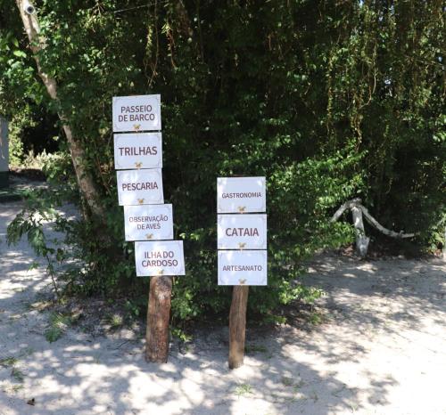a group of signs on posts in front of a tree at Nosso Chalé na Ilha in Cananéia