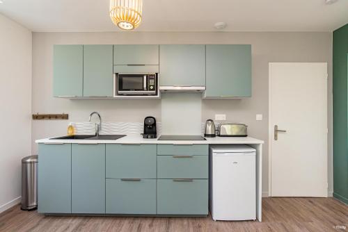 a kitchen with blue cabinets and a microwave at Fontaines de Valence d'Agen Centre Ville Netflix Proche Parking Gratuit in Valence-dʼAgen