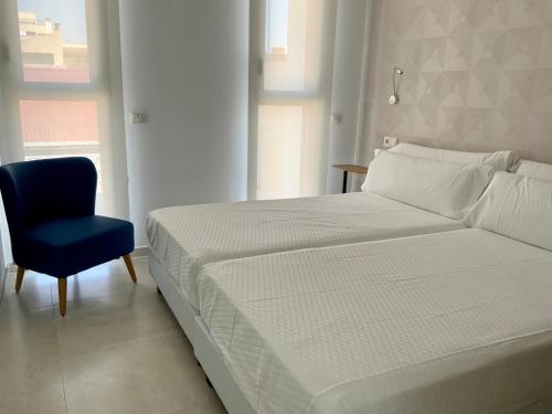 - une chambre avec un lit et une chaise bleue dans l'établissement Apartamentos Rivero 8, à Séville