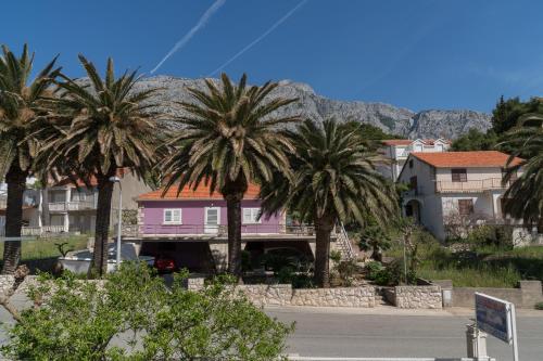 a pink house with palm trees in front of a street at Colonia Apartments in Orebić