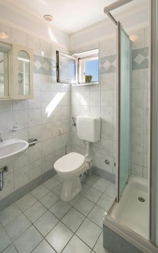 a bathroom with a toilet and a sink and a shower at Colonia Apartments in Orebić