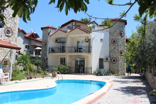 a villa with a swimming pool in front of a house at Dove Apart Hotel in Fethiye