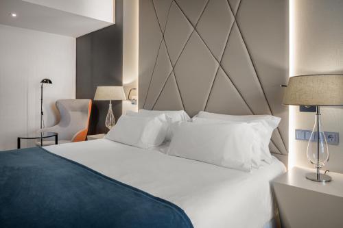 a bedroom with a large white bed with white pillows at NH Collection Salamanca Palacio de Castellanos in Salamanca