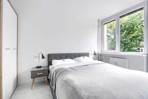 een witte slaapkamer met een bed en een raam bij Apartament Matejki II - Unique Apartments in Szczecin