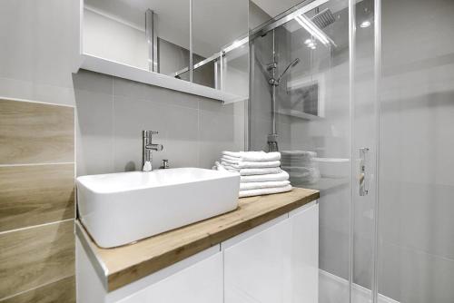 a white bathroom with a sink and a shower at Apartament Matejki II - Unique Apartments in Szczecin