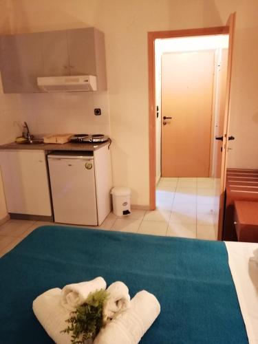 a room with a kitchen with towels on a bed at Hotel Eleni in Paralia Dionysiou