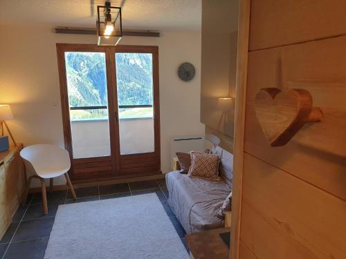 Le lodge by Lilou في مانيجود: غرفة بها نافذة وأريكة وكرسي
