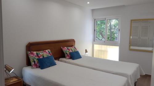 two beds in a white room with a window at Sunshine Apartment in Quarteira