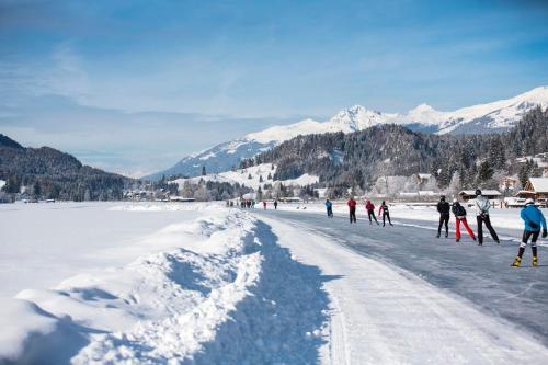 a group of people walking across a snow covered road at Family Home Weißensee in Greifenburg