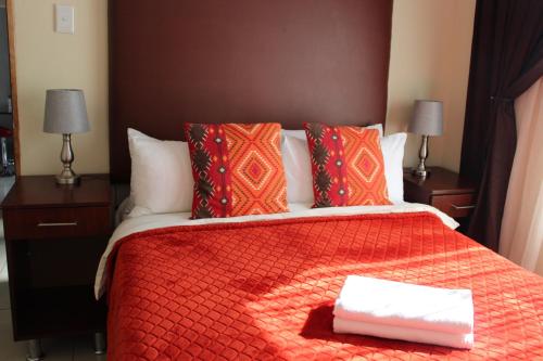 a hotel room with a bed with a red comforter at Bethesda Exclusive Selfcatering Guesthouse, in Phuthaditjhaba