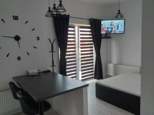 a bedroom with a clock on the wall and a table at Apartamencik na Doby - Lubin in Lubin