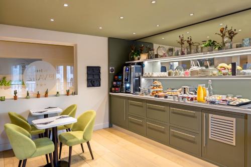 a kitchen with green chairs and a table and a counter at La Valiz in Lille