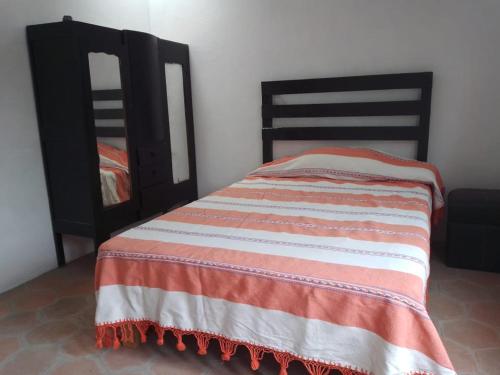 Una cama con una manta naranja y blanca. en Andivi en la ruta dominica, en Yanhuitlán