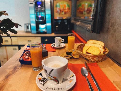 una mesa con una taza de café, pan y zumo de naranja en my HOTEL Bordeaux en Artigues-près-Bordeaux