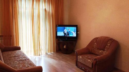 ein Wohnzimmer mit einem TV und 2 Stühlen in der Unterkunft Комната в двухкомнатной in Kiew