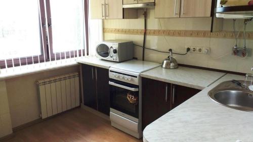eine kleine Küche mit einem Herd und einer Mikrowelle in der Unterkunft Комната в двухкомнатной in Kiew