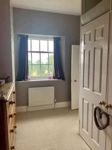 a room with a window with blue curtains and a door at Low Gingerfield Farm B&B in Richmond