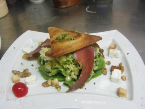 a sandwich on a white plate with a salad and toast at LOGIS-Hôtel Restaurant Auberge Les Vallées Du Perche in Vichères