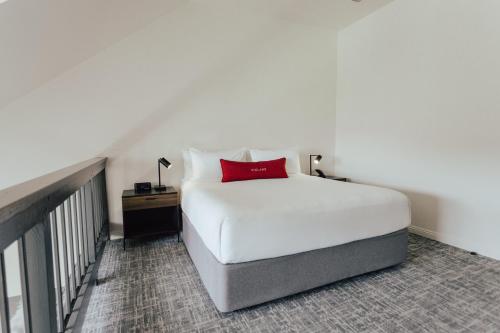 a bedroom with a white bed with a red pillow at Vinland Hotel and Lounge in Solvang
