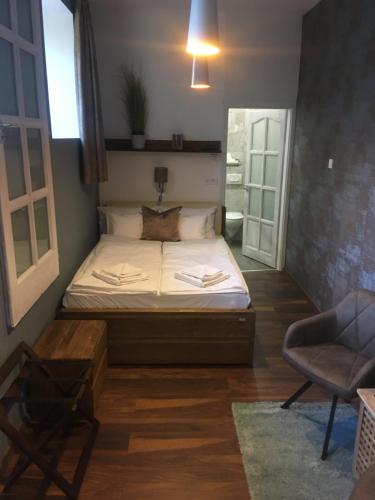 a small bedroom with a bed and a chair at Terrace Apartman Prémium Belváros Jacuzzival in Veszprém
