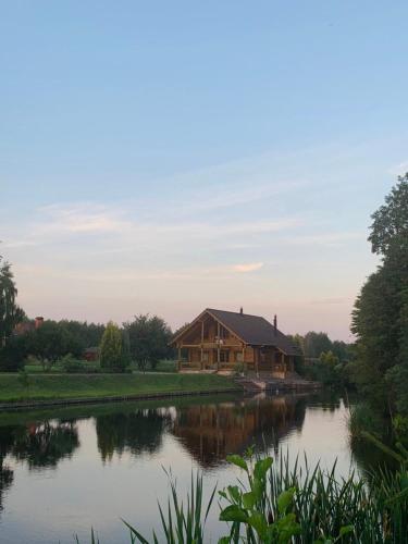 a log cabin by a lake with a house at Фінський будинок для ідеального романтичного чи сімейного відпочинку in Makovishche