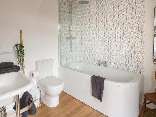 a bathroom with a toilet and a tub and a sink at Monarch's Barn in Droitwich