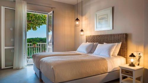 a bedroom with a large bed and a balcony at Beachfront Suites Lourdas in Lourdata