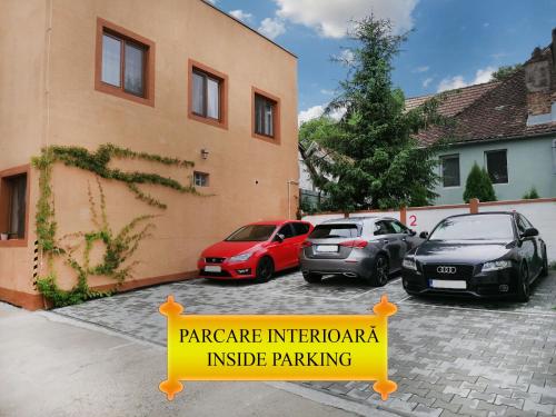 un parking avec des voitures garées devant un bâtiment dans l'établissement Pensiunea Casa Sighisoreana, à Sighişoara
