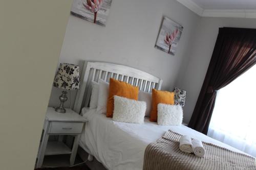 a bedroom with a white bed with pillows and a window at Bethesda Exclusive Selfcatering Guesthouse, in Phuthaditjhaba