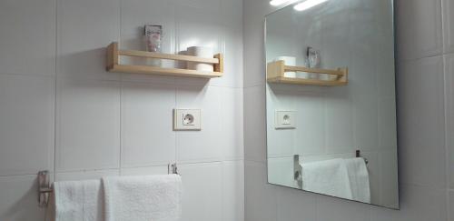 a bathroom with a mirror and white towels at Hostal Meson de Paco in Cariñena