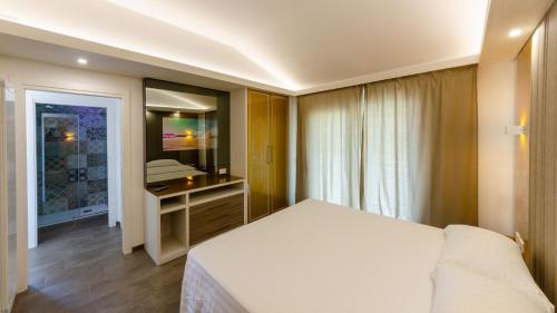 Schlafzimmer mit einem weißen Bett und einem Spiegel in der Unterkunft Calanica Boutique Apartments in Cefalú